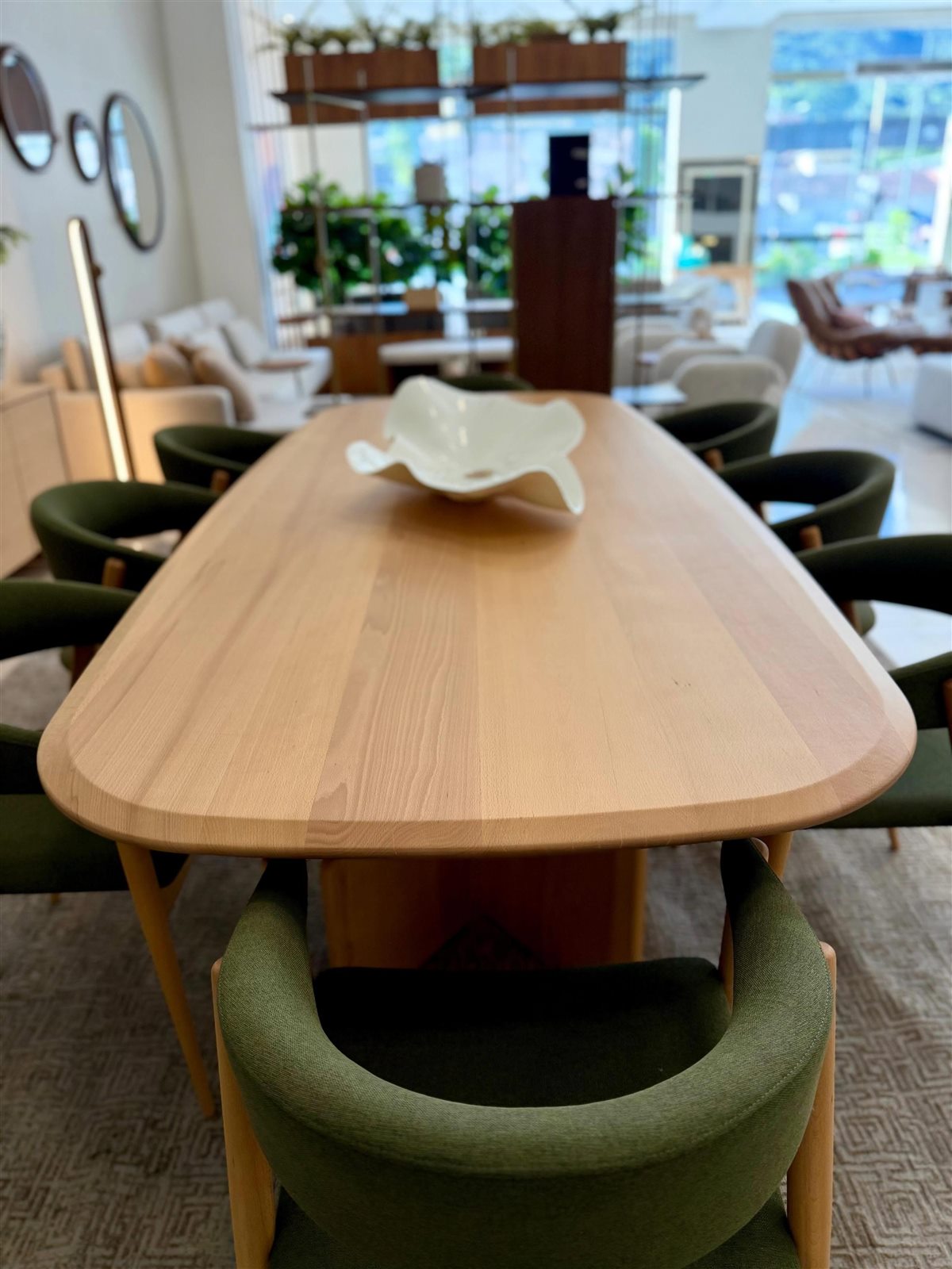 Mesa de madeira clara com cadeiras verdes em showroom