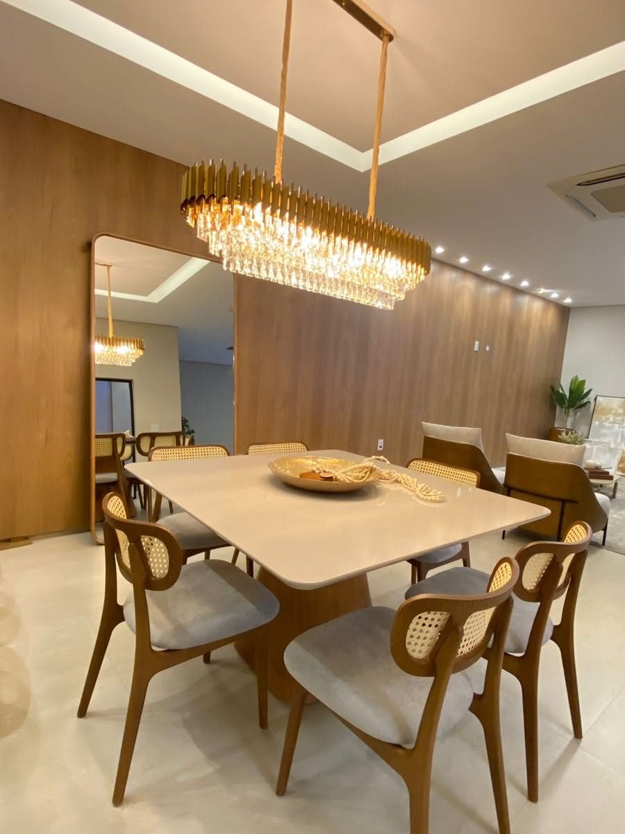 Sala de jantar com lustre dourado e cadeiras em madeira